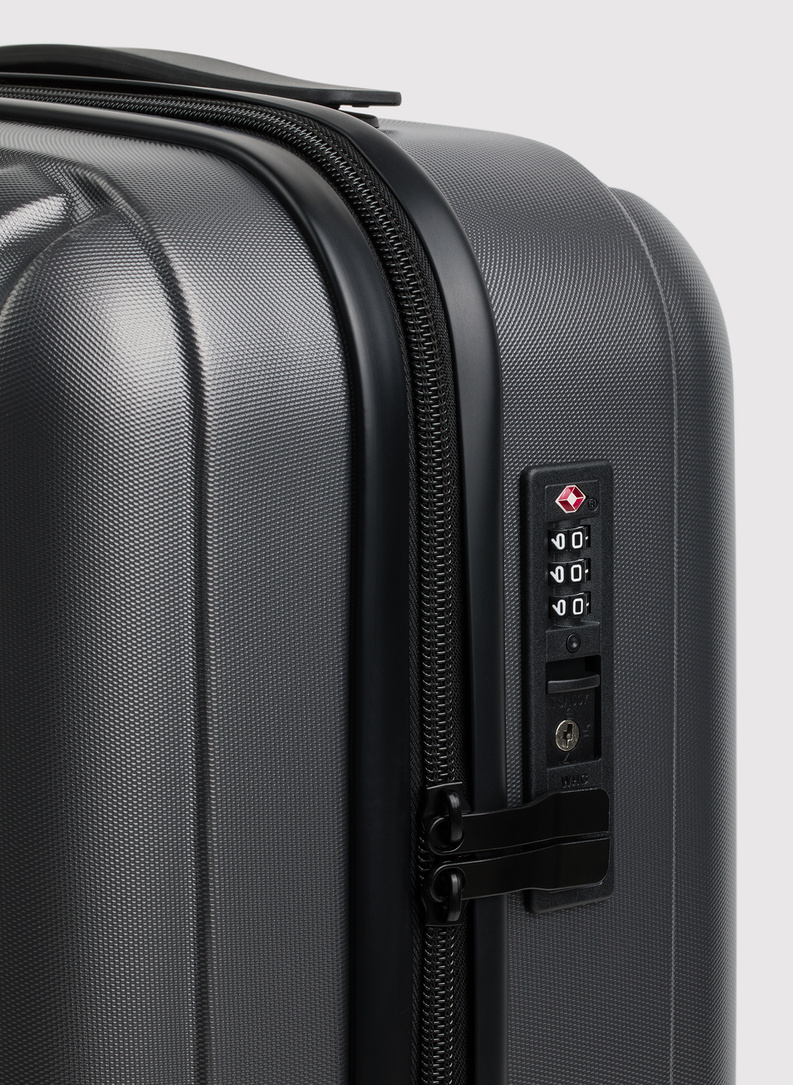 Mažas tamsiai pilkas lagaminas su grioveliais